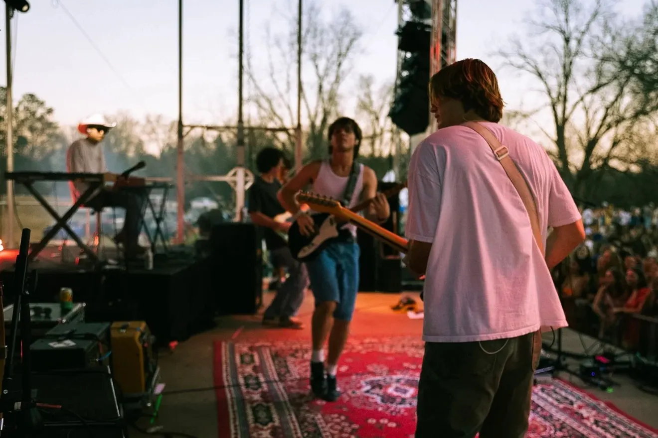 A band plays on a rug-covered stage in late-afternoon light