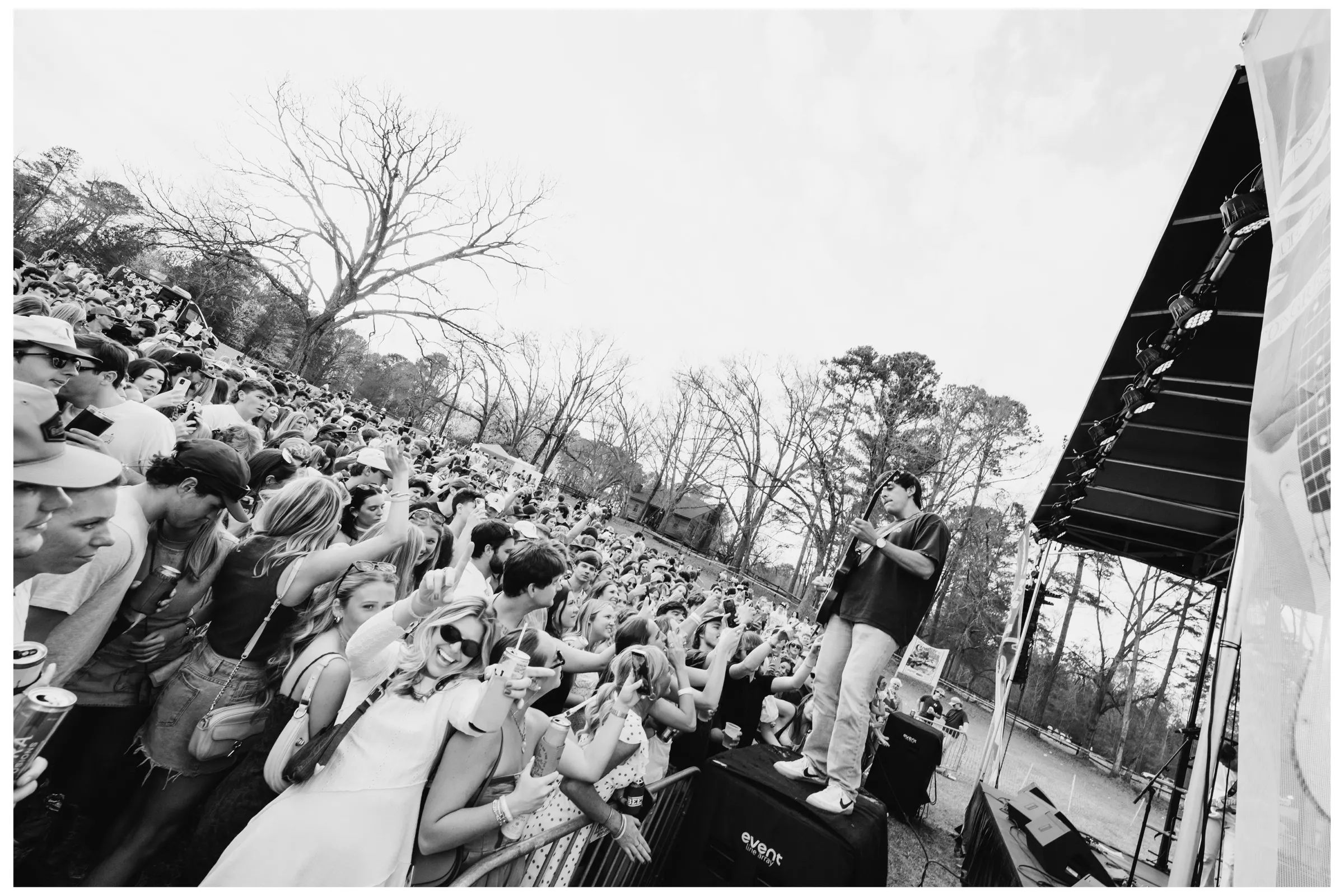 Black-and-white wide shot of the crowd beneath the oaks