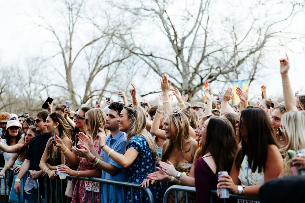 Fans with hands raised at the front of the stage