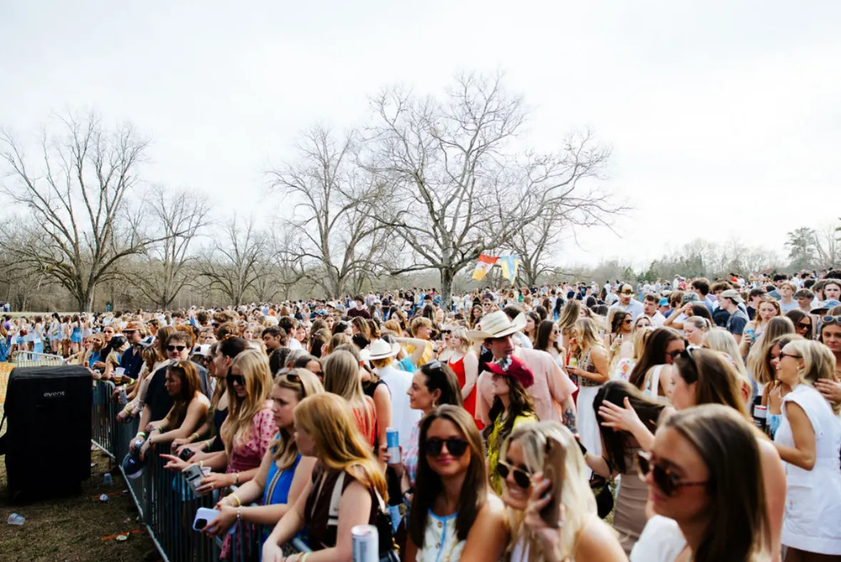 A packed crowd under bare winter oaks