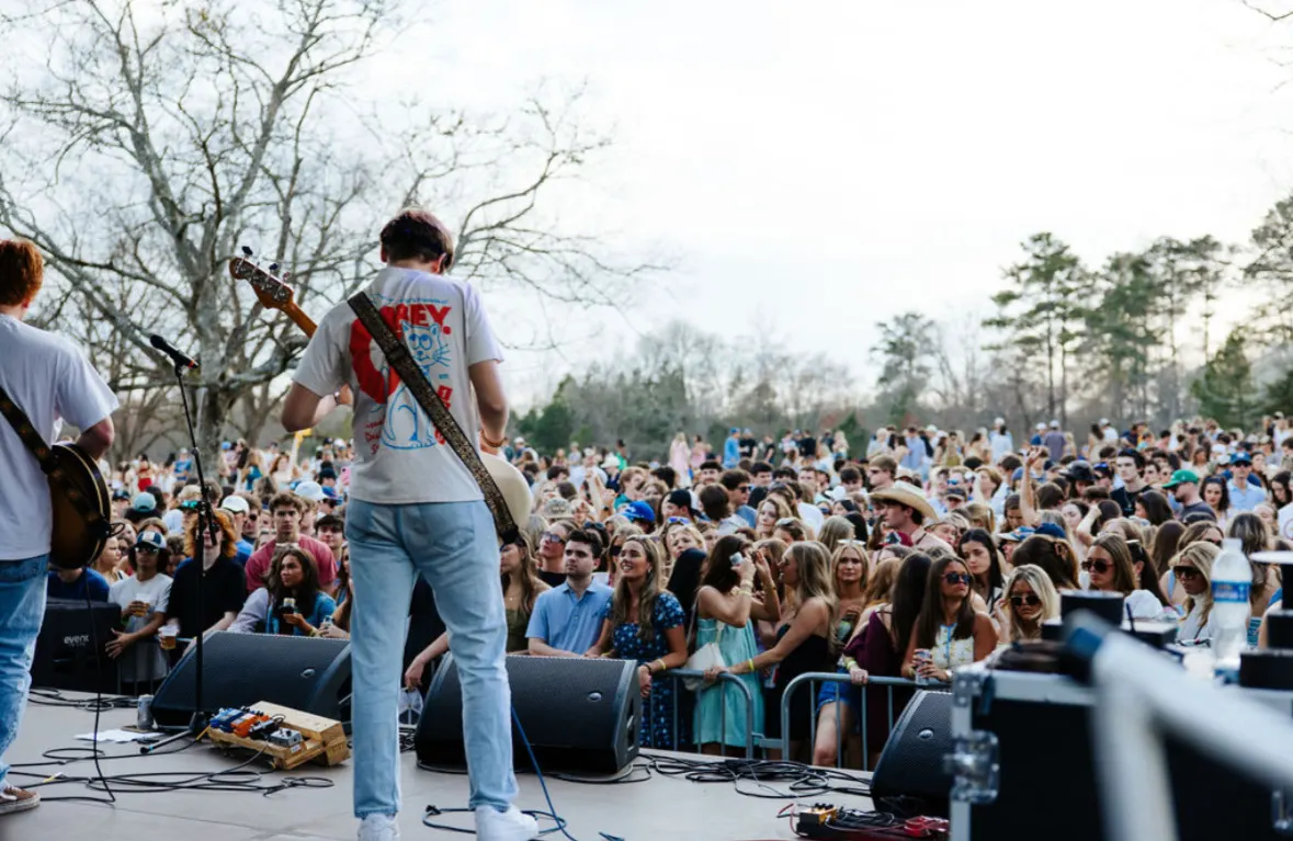 A guitarist faces a sea of fans from the stage